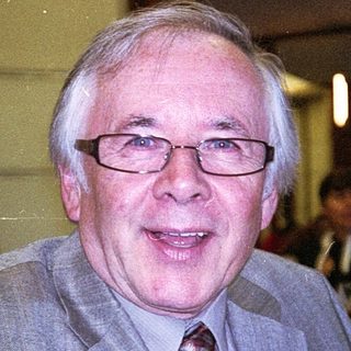 Man in suit smiling indoors at event.
