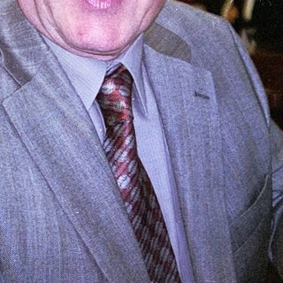 Man in suit smiling indoors at event.