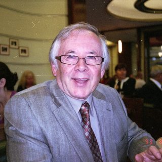 Man in suit smiling indoors at event.