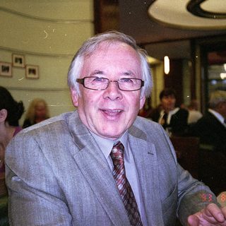 Man in suit smiling indoors at event.