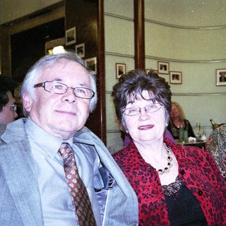 Three adults smiling indoors at an event.