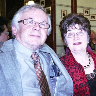 Three adults smiling indoors at an event.