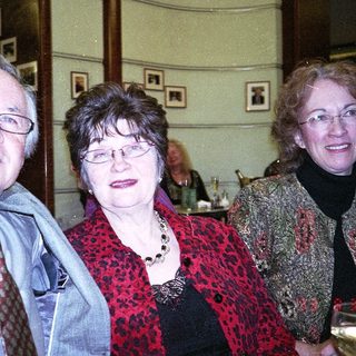 Three adults smiling indoors at an event.