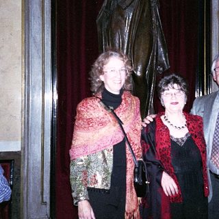 Three people posing indoors near statue.
