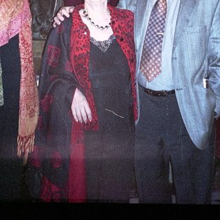 Three adults posing with a statue indoors.