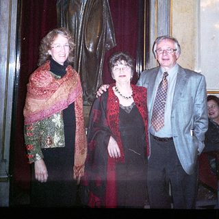 Three adults posing with a statue indoors.