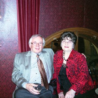 Two people smiling indoors at a cozy table.