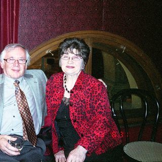 Two people smiling indoors at a cozy table.