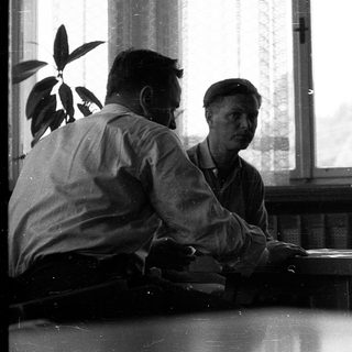 Four men engaged in a serious discussion indoors.
