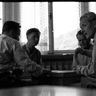 Four men engaged in a serious discussion indoors.