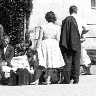 People unloading belongings near a building.