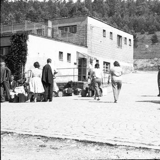 People unloading belongings near a building.
