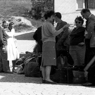 People unloading belongings near a building.