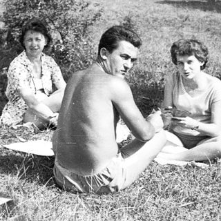 Five people enjoying a picnic outdoors in grassy park.