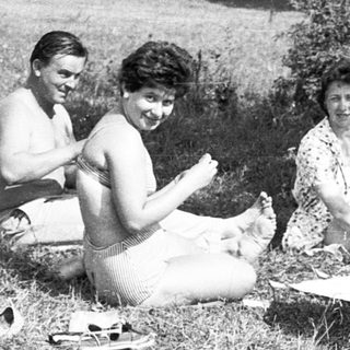 Five people enjoying a picnic outdoors in grassy park.