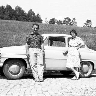 Classic car with two people posing outdoors.