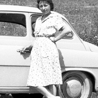 Classic car with two people posing outdoors.