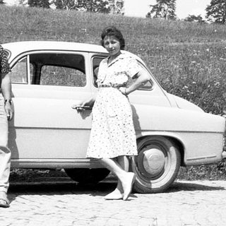 Classic car with two people posing outdoors.