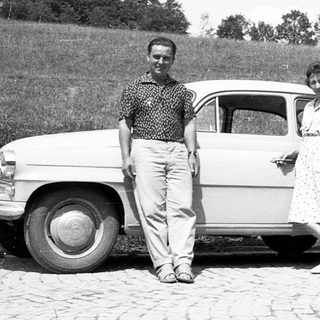 Classic car with two people posing outdoors.