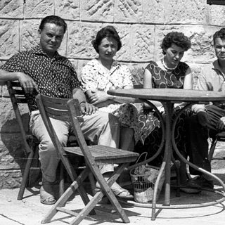 Four people sitting together outdoors at a café table.