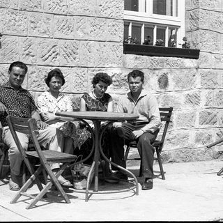 Four people sitting together outdoors at a café table.