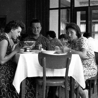 People dining together in a café, mid-20th century.