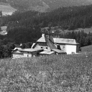 Rural valley with houses, fields, and forested hills.