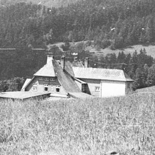 Rural landscape with farm buildings and forested hills.