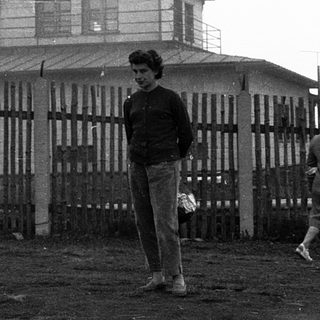 Two people near a watchtower with fenced area.