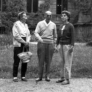 Three people posing outdoors near a historic building.