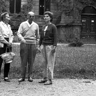 Three people posing outdoors near a historic building.