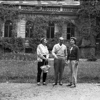 Three people posing outdoors near a historic building.