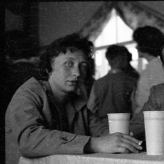 Two people sitting indoors, drinking from cups.