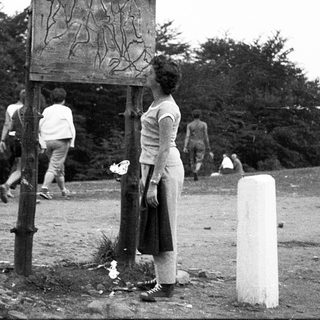 People standing near a wooden signpost in outdoor setting.