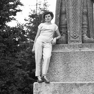 Woman posing beside Komainu guardian lion statue.