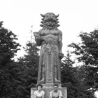 Monument featuring a mythical warrior statue with seated figures.