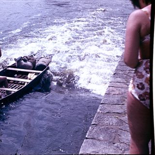 Boat being rowed through turbulent water near shore.