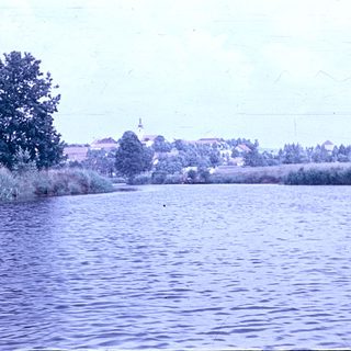 Scenic view of lake with distant church and buildings.