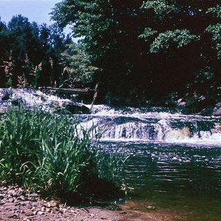Small waterfall cascading over rocky terrain into calm pool.