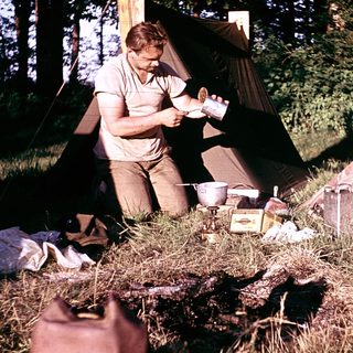 Man preparing food outdoors near camping tent.