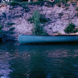 Person standing in shallow river near campsite.