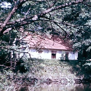 Rustic house beside calm, reflective river.