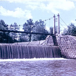 Dam spillway with waterfall and bridge structure.