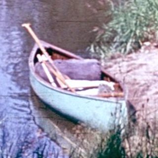 Person sitting in canoe on calm river.