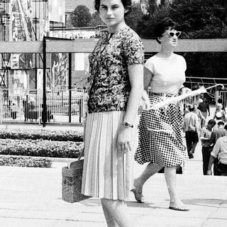 Mid-century outdoor event with modernist architecture and stylish 1960s attire.
