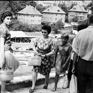 People shopping at an outdoor market with baskets.