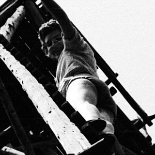 Black-and-white photo of a person atop a wooden tower structure.