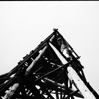 Black-and-white photo of a person atop a wooden tower structure.