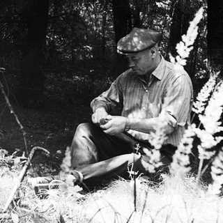 Man sitting outdoors, holding a small object.