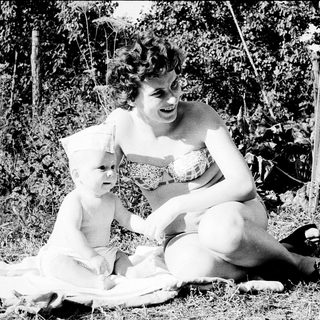 A woman and child sitting outdoors on grass.